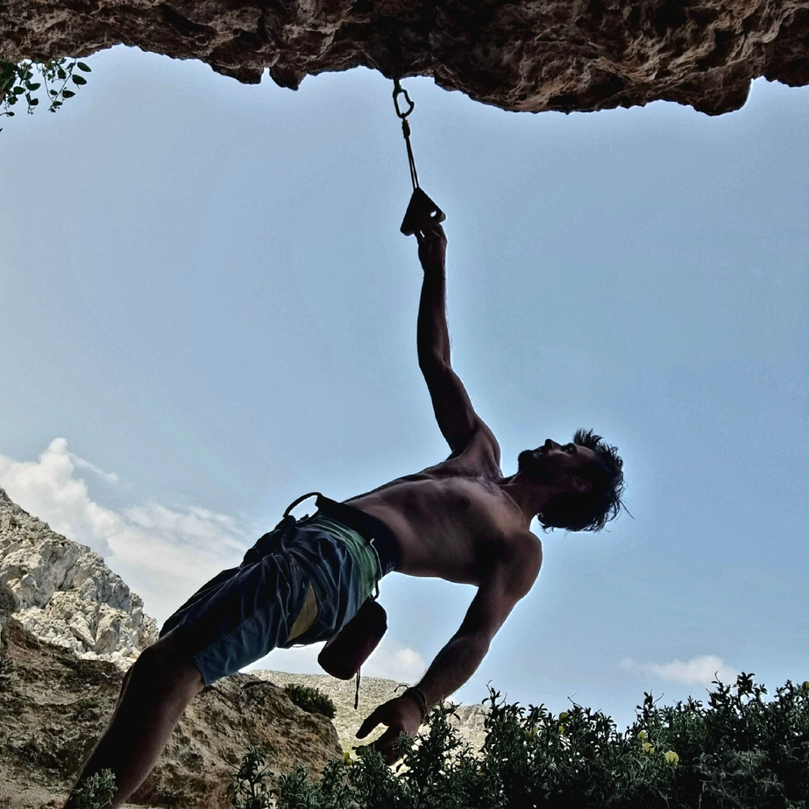 triangle de suspension attaché à la falaise avec un grimpeur qui s'échauffe